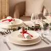 A festive table setting with plates, glasses, napkins, and greenery. Produktbild-Vorschau