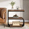A narrow side table with three shelves next to a brown leather sofa. Produktbild-Vorschau