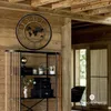 A wall clock with a world map and Roman numerals is displayed on a wooden wall above a shelf unit. Voir les images du produit