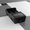 A black battery charger is placed on a surface with a geometric pattern of white, gray, and black squares. Anteprima dell’immagine prodotto