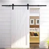 A white barn door with black hardware is partially open, revealing a bedroom interior with a bed and sofa. Podgląd zdjęcia produktu