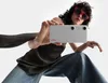 A person wearing sunglasses and jeans holds up a white device with two cameras and the XREAL logo. Anteprima dell’immagine prodotto