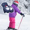 A child wearing ski gear and holding ski poles on a snowy slope, with a close-up inset of a pair of children's mittens with a snowman design. Náhled obrázku produktu