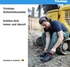 A man is tying his shoelaces on a construction site next to a yellow excavator. Produktbild-Vorschau