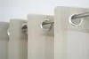 A close-up view of several eyelet curtains hanging on a metal rod against a white background.