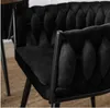 Close-up of a black velvet armchair with a tufted backrest and black metal legs, placed on a woven rug. Náhľad obrázku produktu