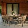A patio dining set with chairs and a table, set up on a tiled patio next to a wooden-paneled wall. Produktbild-Vorschau