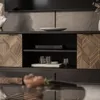 A close-up view of a modern TV stand with decorative wooden doors and shelves displaying electronic devices and decorative items. Produktbild-Vorschau