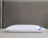 A white pillow is placed on a surface in front of a gray headboard. Produktbild-Vorschau