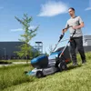 A man is mowing a grassy hill with a Bosch cordless lawnmower. Voir les images du produit