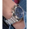 A close-up shot of a woman's wrist wearing a silver Guess watch with a blue dial. Voir les images du produit