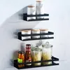 Three black shelves mounted on a marble-tiled wall, displaying various kitchen/bathroom items. Náhled obrázku produktu