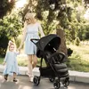 A woman and a child walking with a stroller in a park. Produktbild-Vorschau