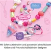 A collection of colorful beads and jewelry-making supplies arranged on a pink background. Anteprima dell’immagine prodotto