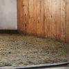The image shows the floor of a stable or barn, covered with straw-based bedding material, with a wooden wall in the background. Produktbild-Vorschau