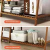 A split image showing two levels of a bamboo shelving unit, one with folded clothes and laundry bags, the other with storage boxes and shoes. Voir les images du produit