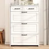 A white shoe cabinet with black handles is shown in a room with a wooden floor and a stool to the left. Produktbild-Vorschau