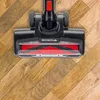 A close-up view of a vacuum cleaner head on a wooden floor. Anteprima dell’immagine prodotto