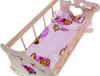 A wooden doll cradle with pink bedding featuring cartoon characters. Náhľad obrázku produktu
