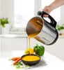 A hand is pouring soup from a soup maker into a bowl, with vegetables in the foreground. Anteprima dell’immagine prodotto