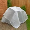 A transparent tarp covers an outdoor furniture item, placed on a paved patio next to a brick wall and a wooden fence. Anteprima dell’immagine prodotto