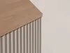 A close-up view of a cabinet with a wooden top and fluted front panels. Podgląd zdjęcia produktu