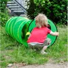 A child is playing with a green tunnel in a grassy outdoor area. Produktbild-Vorschau