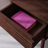 A close-up view of an open drawer in a wooden nightstand, with a purple book inside. Produktbild-Vorschau