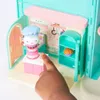 A child's hand is interacting with a toy kitchen playset, specifically a cake-themed room. Produktbild-Vorschau