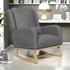 A gray teddy plush rocking chair with wooden legs is shown in a room with a bookshelf in the background. Produktbild-Vorschau