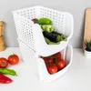 Two white stacking storage baskets filled with fresh produce, including tomatoes, peppers, and eggplants, on a white countertop. Anteprima dell’immagine prodotto