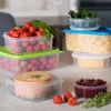 A collection of food storage containers filled with various food items, including strawberries, pasta, cheese, and jam, arranged on a countertop. Produktbild-Vorschau