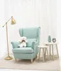 A teddy bear sits on a light blue armchair next to two small side tables, with a floor lamp to the left and white curtains in the background. Podgląd zdjęcia produktu