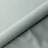 A rolled-up piece of light gray fabric, likely upholstery or bedding material, is shown diagonally across the frame. The fabric has a soft, matte texture. Produktbild-Vorschau