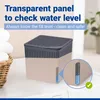 A dehumidifier sits on a washing machine next to a basket of towels. A close-up inset shows the water level indicator. Podgląd zdjęcia produktu