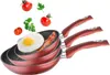 A set of three red frying pans with an egg and bacon in the top pan, and tomatoes and parsley floating above. Produktbild-Vorschau