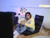 A young man playing a video game on a floor chair in a dimly lit room. Náhľad obrázku produktu