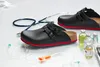 A pair of black clogs with red soles and medical supplies, including a stethoscope and IV bags, are arranged on a white surface. Anteprima dell’immagine prodotto