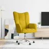 A yellow velvet armchair with a chrome base and wheels is shown in a living room setting, with a floor lamp and abstract art in the background. Voir les images du produit