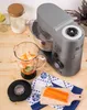 A kitchen mixer with a blender attachment filled with fruit, next to chopped carrots and a jar of flour. Podgląd zdjęcia produktu