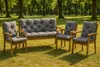 A garden bench and two chairs with gray cushions are placed on a grassy lawn in a park-like setting with trees in the background. Produktbild-Vorschau