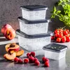 A set of four square food storage containers with dark gray lids, stacked on a gray surface. Peaches, sliced peaches, and raspberries are arranged in the foreground, and cherry tomatoes and basil are in the background. Náhľad obrázku produktu