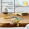 A 3D printed dragon figurine with a rainbow color gradient is displayed on a wooden surface, with an open book and a vase in the background. Text overlays highlight 'REALISTISCHES DESIGN' and 'REALISTIC DESIGN'. Produktbild-Vorschau