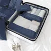 A neatly packed suitcase with various organizer bags filled with clothes and accessories, along with a pair of white sneakers placed beside it. Anteprima dell’immagine prodotto