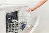 A hand is placing a clear plastic container into a dishwasher. Voir les images du produit