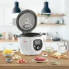 A white Tefal Cook4me+ smart multi-function cooker is displayed on a wooden countertop, with various ingredients arranged around it, suggesting it's ready for cooking. Podgląd zdjęcia produktu
