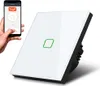 A hand holding a smartphone displaying the Tuya app, next to a smart WiFi touch light switch. Voir les images du produit