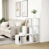 A white modular shelving unit is placed next to a sofa in a living room. Voir les images du produit