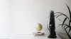 A handheld vacuum cleaner is displayed on a white surface next to a globe and some books, with a plant in the background. Podgląd zdjęcia produktu