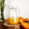 A glass pitcher filled with orange juice sits on a wooden coaster, surrounded by sliced oranges and lemons. Podgląd zdjęcia produktu